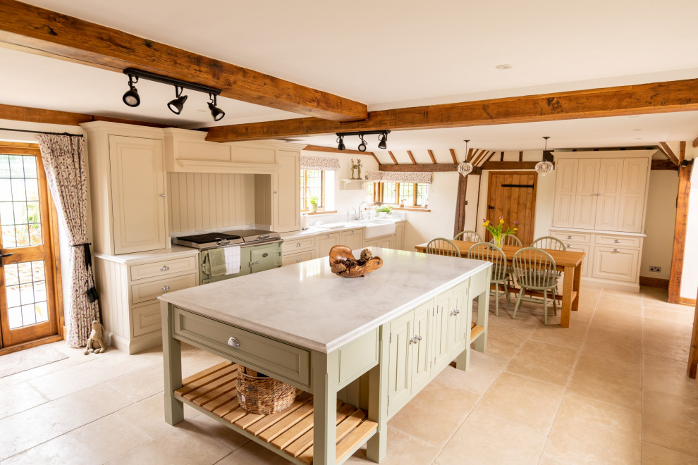 Photo of an expansive traditional galley open plan kitchen in Essex with a double-bowl sink, raised-panel cabinets, green cabinets, quartzite benchtops, coloured appliances, porcelain floors, with island, beige floor, white benchtop and exposed beam.