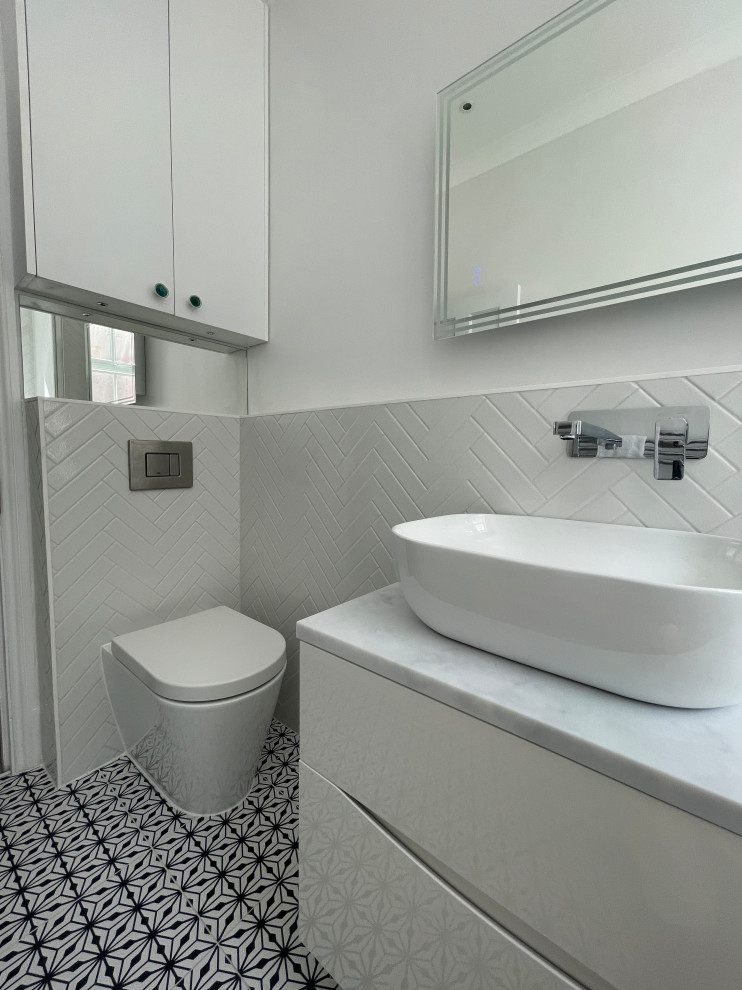 Свежая идея для дизайна: детская ванная комната среднего размера: освещение в современном стиле с плоскими фасадами, белыми фасадами, японской ванной, душем над ванной, инсталляцией, белой плиткой, керамогранитной плиткой, белыми стенами, полом из керамической плитки, настольной раковиной, столешницей из кварцита, черным полом, душем с распашными дверями, серой столешницей, тумбой под одну раковину и подвесной тумбой - отличное фото интерьера