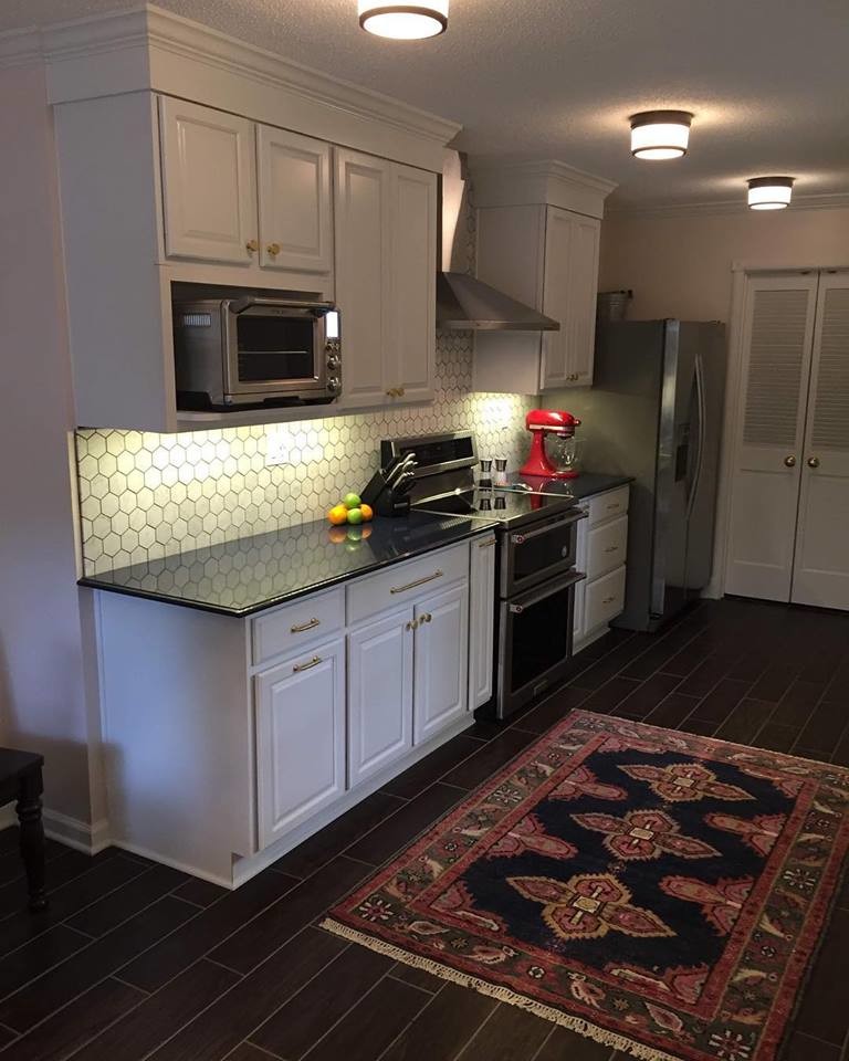Example of a small eclectic galley porcelain tile and brown floor enclosed kitchen design with an undermount sink, raised-panel cabinets, white cabinets, quartz countertops, white backsplash, marble backsplash, stainless steel appliances, no island and blue countertops