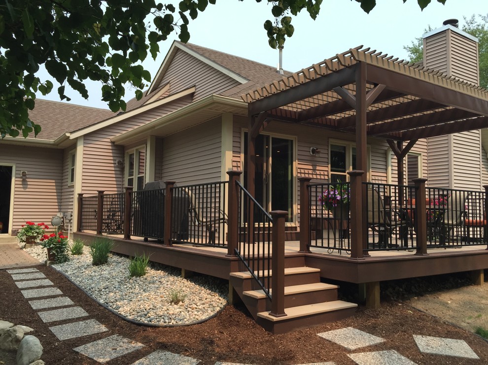This is an example of a mid-sized arts and crafts backyard deck in Grand Rapids with a pergola.