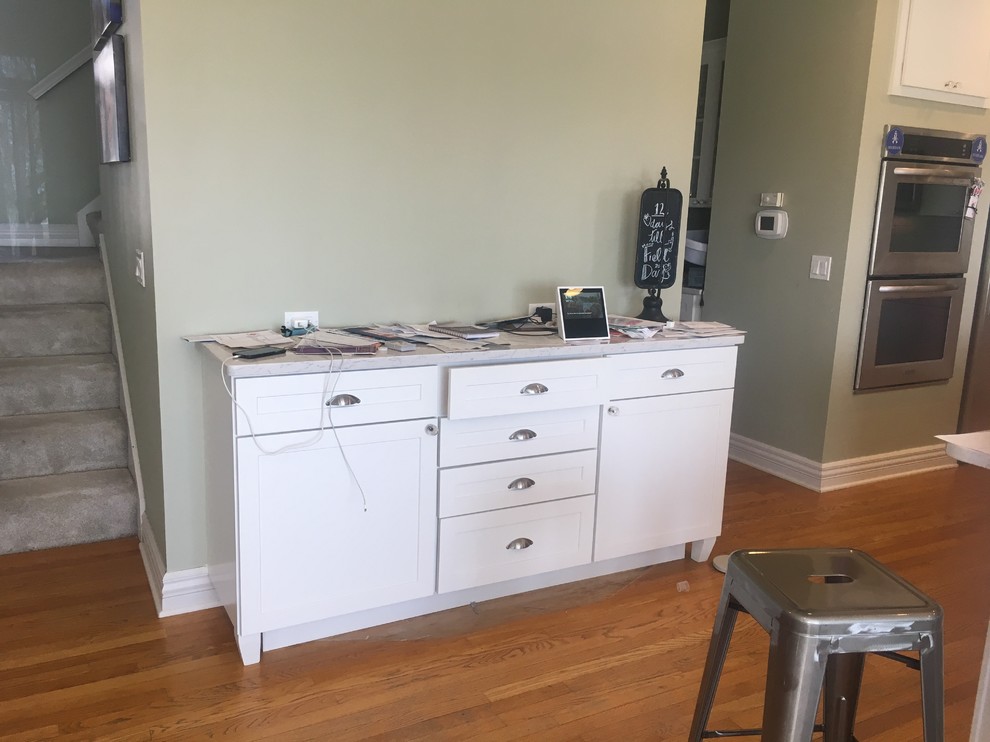 Inspiration for a large transitional l-shaped medium tone wood floor and brown floor open concept kitchen remodel in Omaha with a farmhouse sink, shaker cabinets, white cabinets, quartz countertops, white backsplash, ceramic backsplash, stainless steel appliances, two islands and white countertops