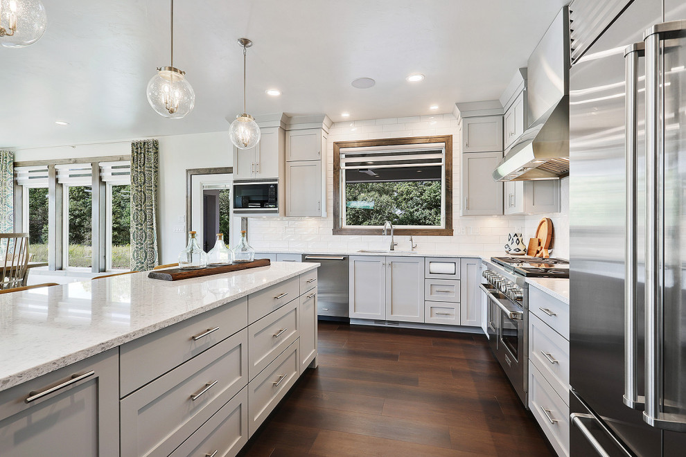 Inspiration for a mid-sized transitional u-shaped brown floor and dark wood floor open concept kitchen remodel with gray walls, an undermount sink, gray cabinets, quartz countertops, white backsplash, stainless steel appliances, an island, white countertops, recessed-panel cabinets and subway tile backsplash