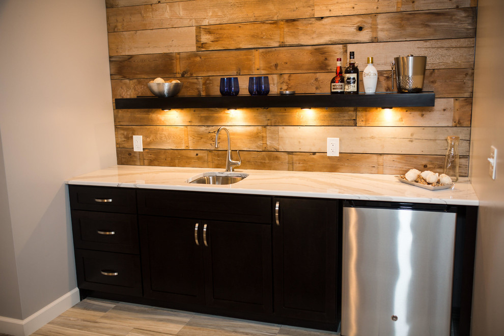 This is an example of a mid-sized country single-wall wet bar in Omaha with an undermount sink, flat-panel cabinets, black cabinets, marble benchtops, brown splashback, timber splashback and light hardwood floors.