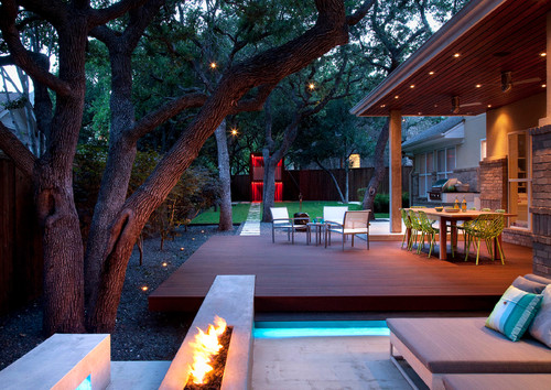 Sleek style defines this rich wood floating deck. While it may be attached to the home, it extends well into the yard and is bordered by a water feature and outdoor fireplace.