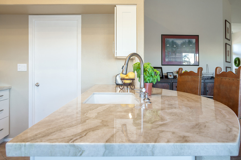 Transitional galley ceramic tile home design photo in Phoenix with an undermount sink, recessed-panel cabinets, white cabinets, quartz countertops, white backsplash, ceramic backsplash, stainless steel appliances and an island