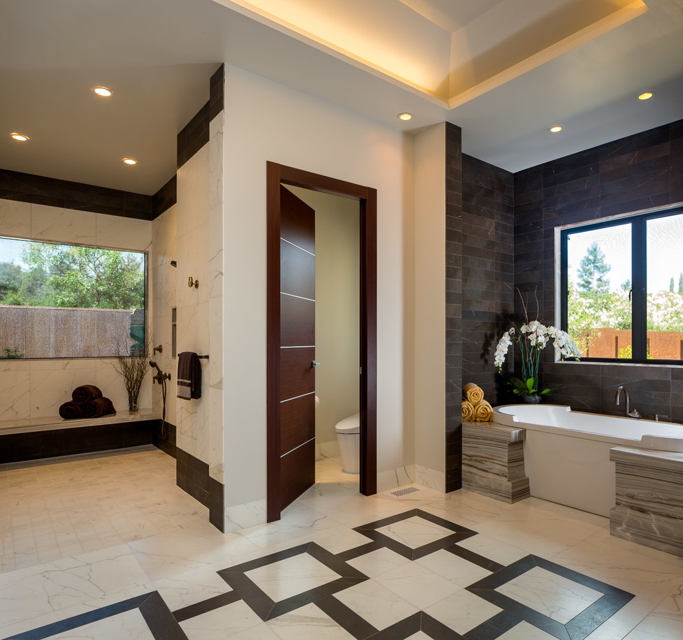 Photo of an expansive contemporary master bathroom in San Francisco with flat-panel cabinets, brown cabinets, a freestanding tub, a curbless shower, a one-piece toilet, black and white tile, stone tile, beige walls, marble floors, an undermount sink and marble benchtops.