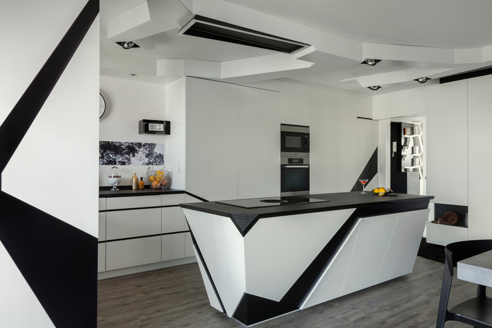 Large contemporary l-shaped open plan kitchen in Paris with flat-panel cabinets, with island, a double-bowl sink, white splashback, stainless steel appliances, painted wood floors, grey floor and black benchtop.