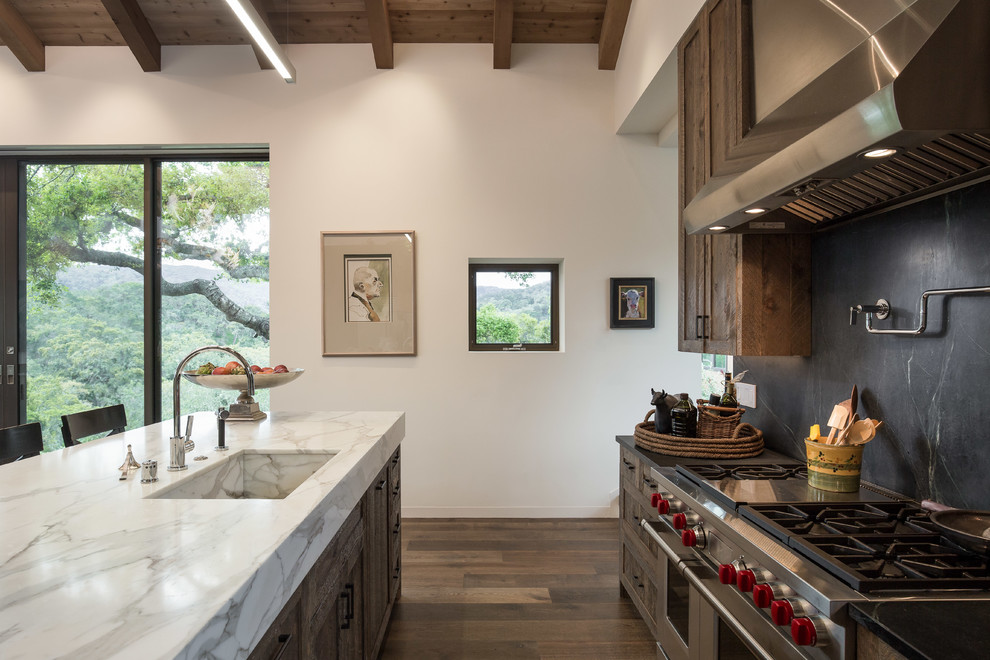 Inspiration for a mid-sized transitional l-shaped kitchen in San Francisco with an undermount sink, white cabinets, marble benchtops, black splashback, marble splashback, stainless steel appliances, medium hardwood floors, with island, brown floor and white benchtop.
