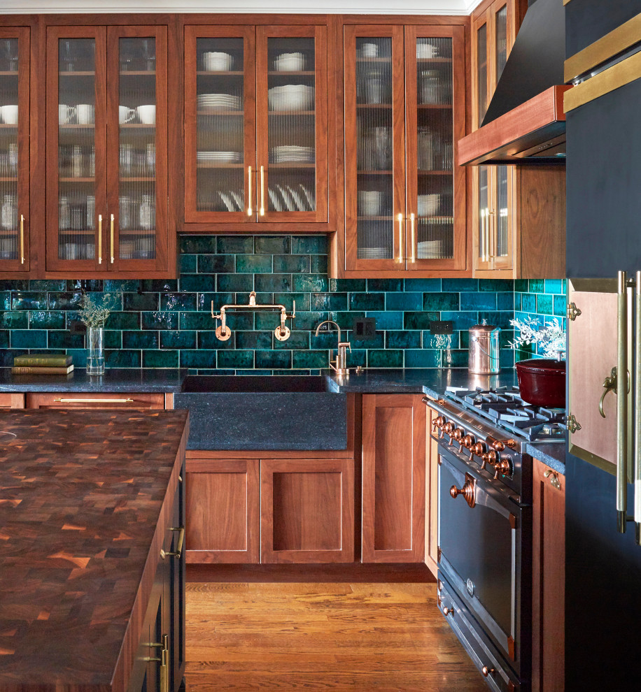 Modelo de cocina de estilo americano con puertas de armario de madera oscura, salpicadero gris, salpicadero de azulejos tipo metro, electrodomésticos negros, suelo de madera en tonos medios y una isla