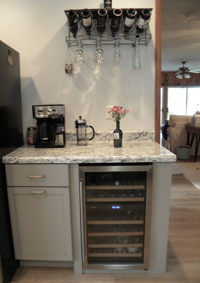 Example of a large transitional single-wall light wood floor and yellow floor kitchen pantry design with a drop-in sink, recessed-panel cabinets, white cabinets, blue backsplash, ceramic backsplash, stainless steel appliances, no island and gray countertops