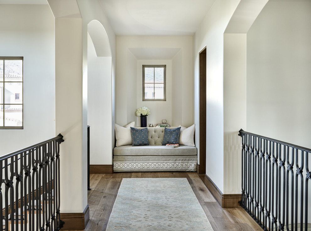 This is an example of a mid-sized mediterranean hallway in Chicago with white walls, medium hardwood floors and brown floor.