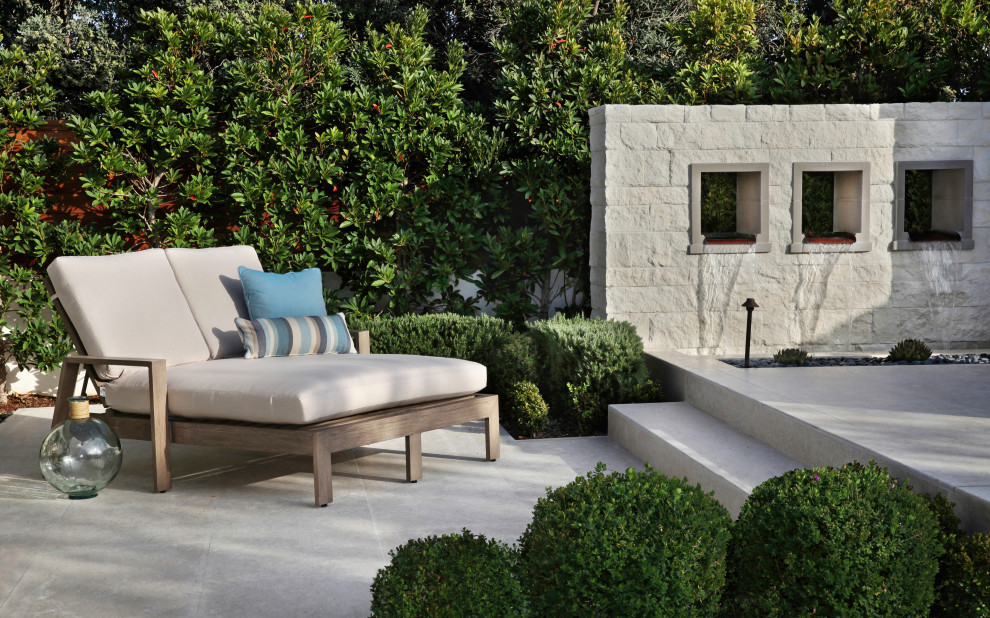 Inspiration for a large contemporary courtyard patio in Orange County with a water feature and natural stone pavers.