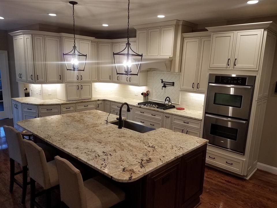 This is an example of a large traditional u-shaped eat-in kitchen in Raleigh with a farmhouse sink, flat-panel cabinets, beige cabinets, granite benchtops, beige splashback, porcelain splashback, stainless steel appliances, medium hardwood floors and multiple islands.