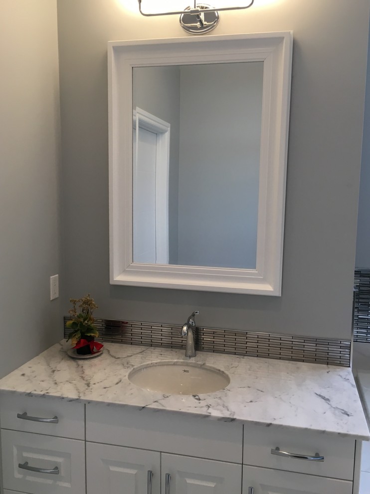 Mid-sized arts and crafts master bathroom in Edmonton with raised-panel cabinets, white cabinets, a drop-in tub, an alcove shower, grey walls, marble floors, an undermount sink and marble benchtops.