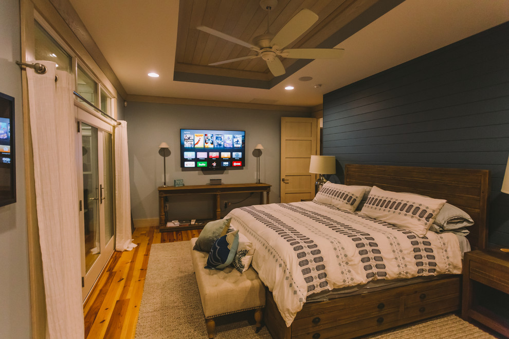 This is an example of a mid-sized beach style guest bedroom in Other with green walls, medium hardwood floors, no fireplace and brown floor.