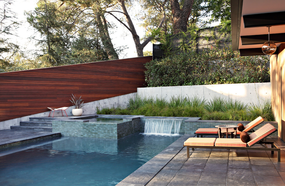 Photo of a midcentury backyard l-shaped pool in Los Angeles with a water feature.