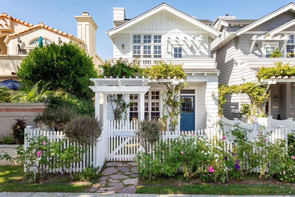 Example of a beach style white two-story exterior home design in San Diego with a shingle roof