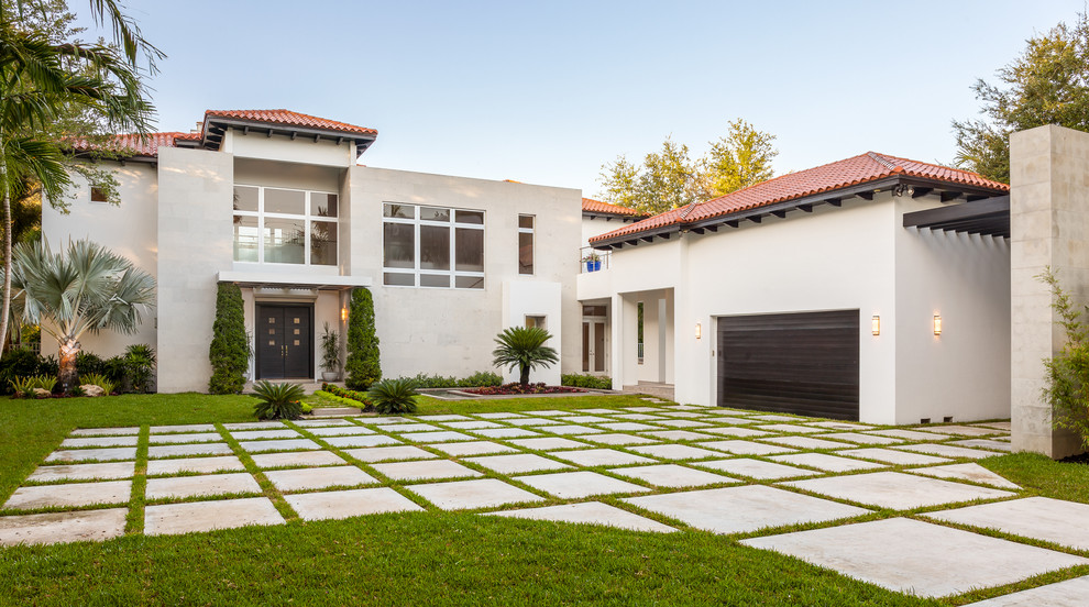 Large mediterranean two-storey stucco beige house exterior in Miami with a hip roof and a tile roof.