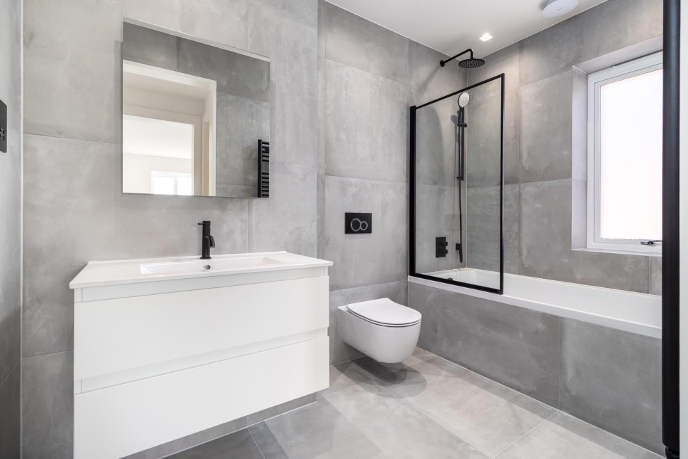 Exempel på ett mellanstort modernt vit vitt en-suite badrum, med vita skåp, ett platsbyggt badkar, en dusch/badkar-kombination, en toalettstol med hel cisternkåpa, grå kakel, porslinskakel, grå väggar, klinkergolv i porslin, ett väggmonterat handfat, bänkskiva i akrylsten, grått golv och dusch med gångjärnsdörr