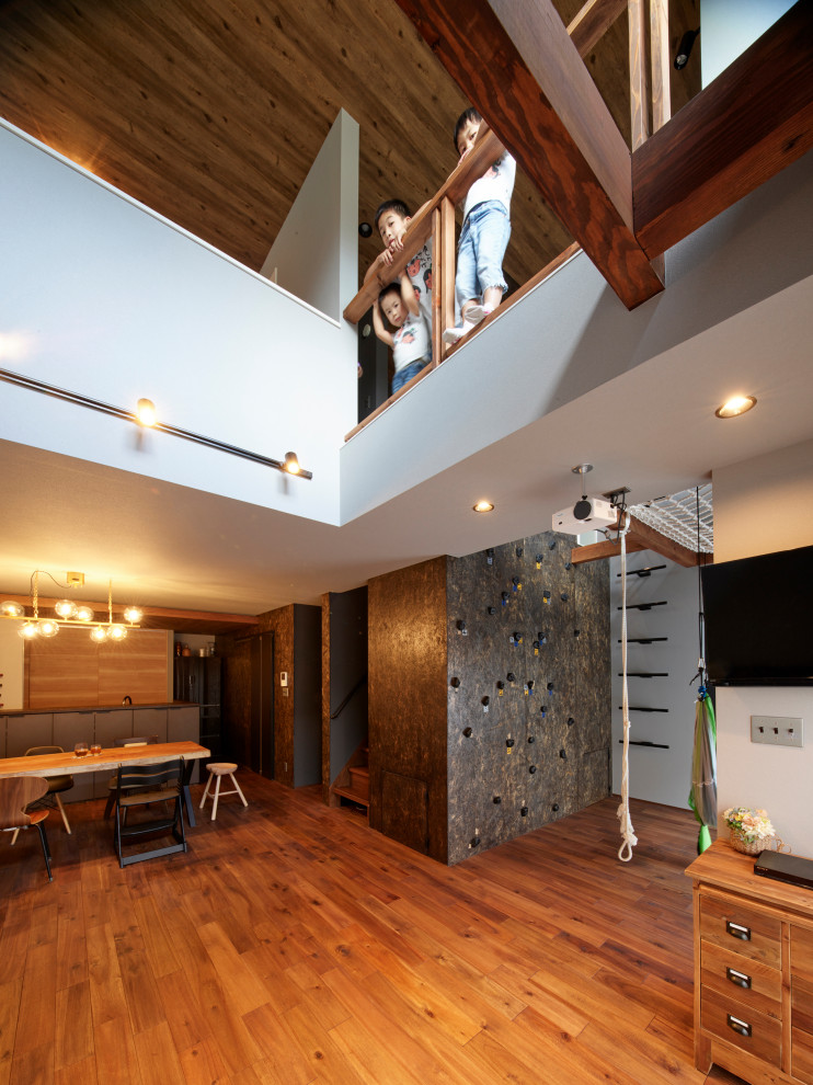Inredning av ett mellanstort allrum med öppen planlösning, med grå väggar, mörkt trägolv, en väggmonterad TV och brunt golv