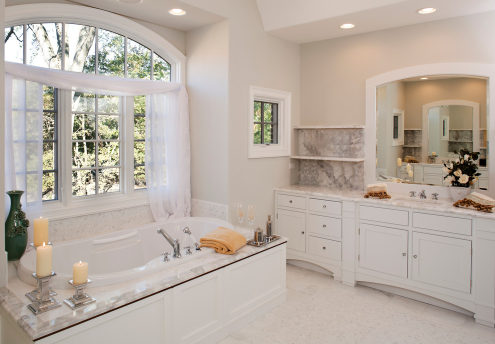Mid-sized contemporary master bathroom in Los Angeles with furniture-like cabinets, white cabinets, a freestanding tub, marble floors, marble benchtops and white floor.