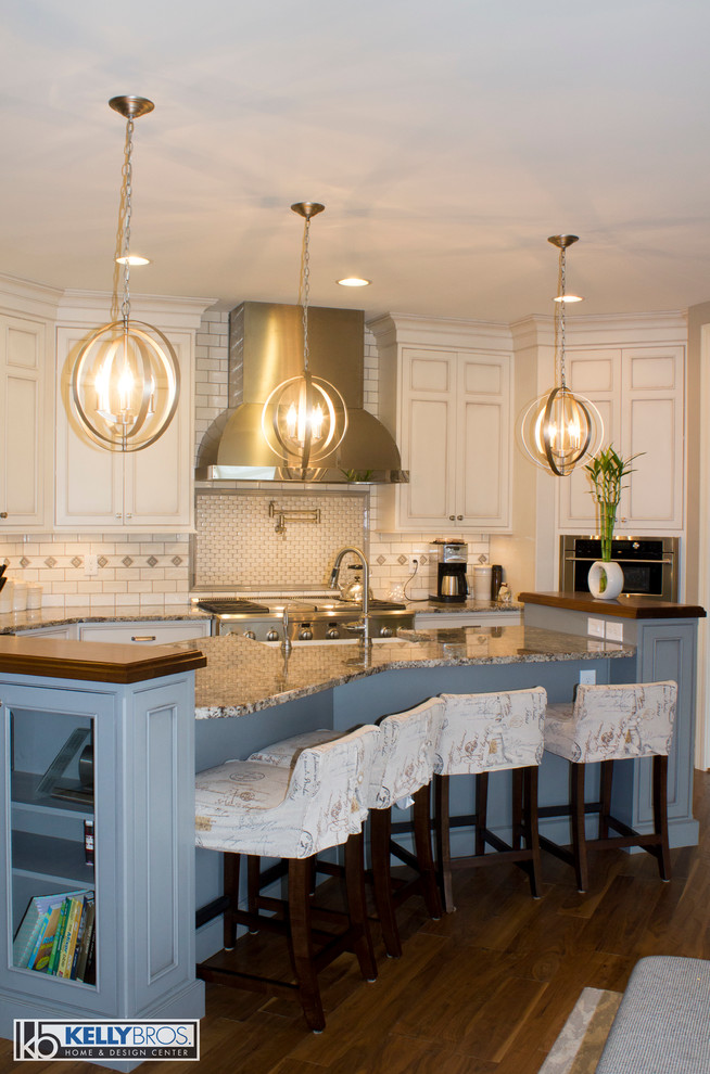 This is an example of a large transitional u-shaped eat-in kitchen in Cincinnati with a farmhouse sink, beaded inset cabinets, white cabinets, granite benchtops, white splashback, ceramic splashback, stainless steel appliances, medium hardwood floors and with island.