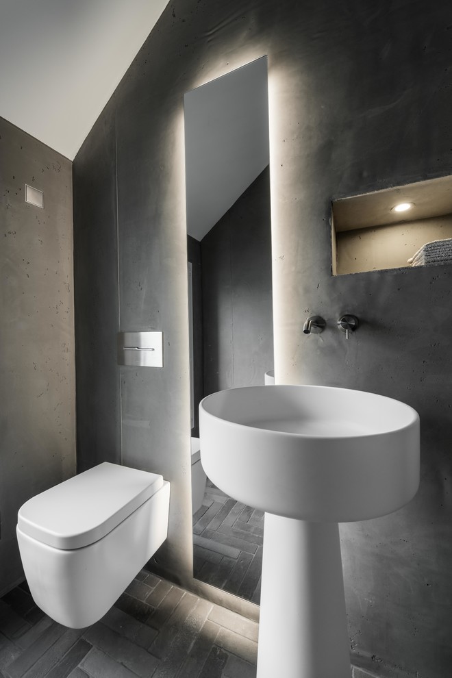 Inspiration for a small modern powder room in Bonn with a wall-mount toilet, grey walls, concrete floors, a pedestal sink, grey floor and solid surface benchtops.