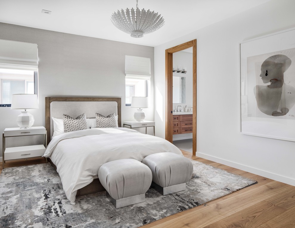 This is an example of a contemporary master bedroom in Los Angeles with white walls, medium hardwood floors and brown floor.