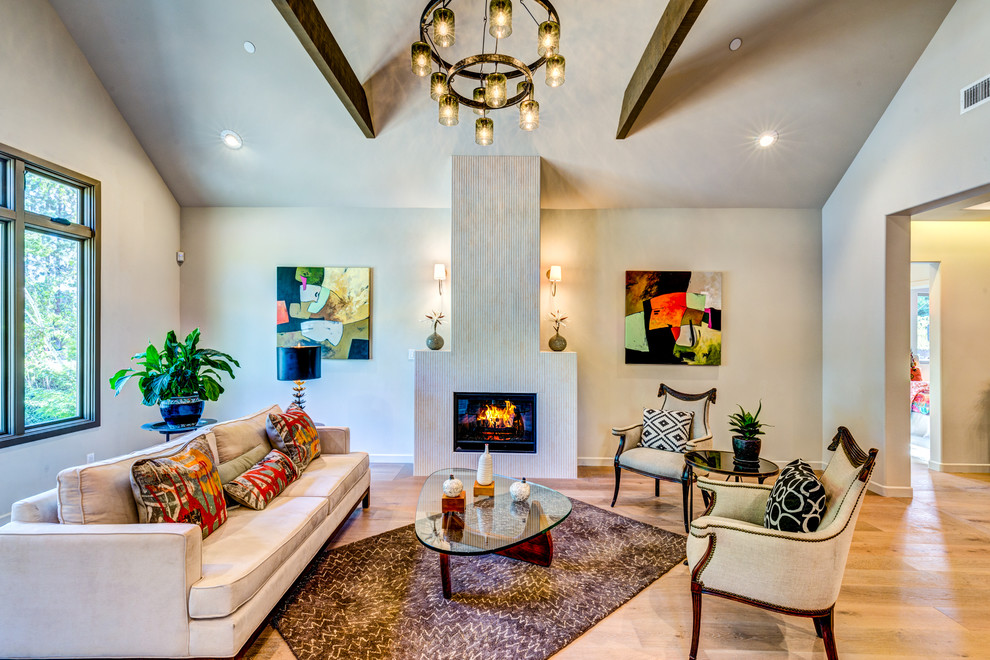 Inspiration for a large transitional formal open concept living room in Los Angeles with light hardwood floors, a standard fireplace, no tv, beige walls and a concrete fireplace surround.