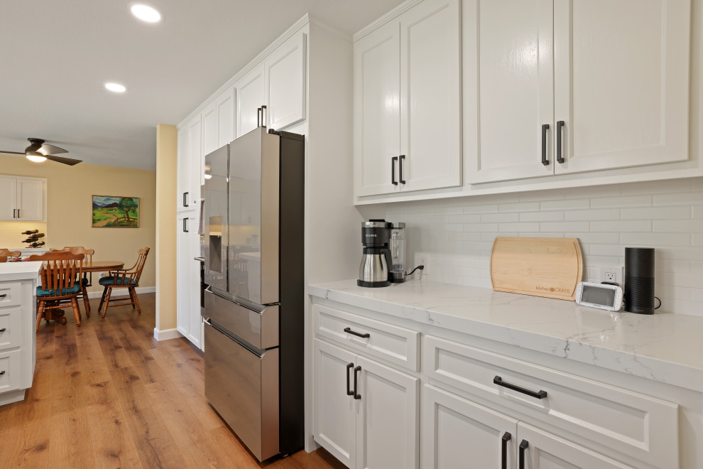 Inspiration for a modern kitchen remodel in Sacramento with an undermount sink, white cabinets, quartz countertops, white backsplash, ceramic backsplash, stainless steel appliances and white countertops