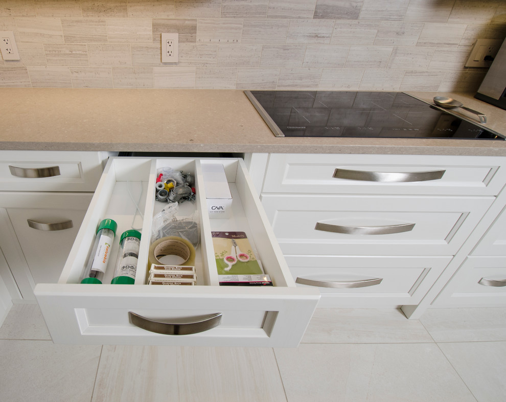 Inspiration for a transitional u-shaped limestone floor eat-in kitchen remodel with an undermount sink, raised-panel cabinets, gray cabinets, quartz countertops, beige backsplash, stone tile backsplash, stainless steel appliances and an island
