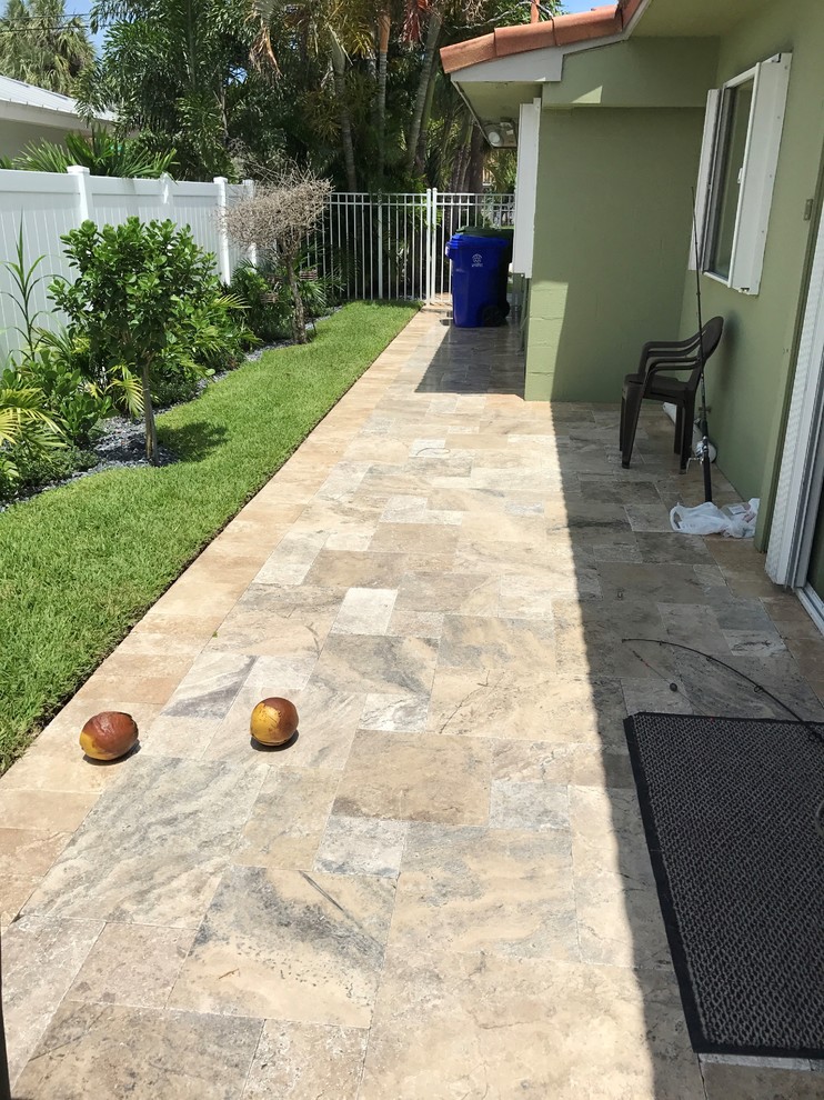 This is an example of a large contemporary backyard rectangular aboveground pool in Miami with natural stone pavers.