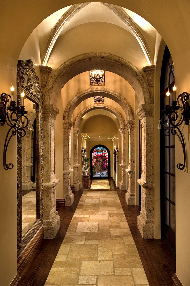 Expansive mediterranean hallway in Phoenix with multi-coloured walls, multi-coloured floor and travertine floors.