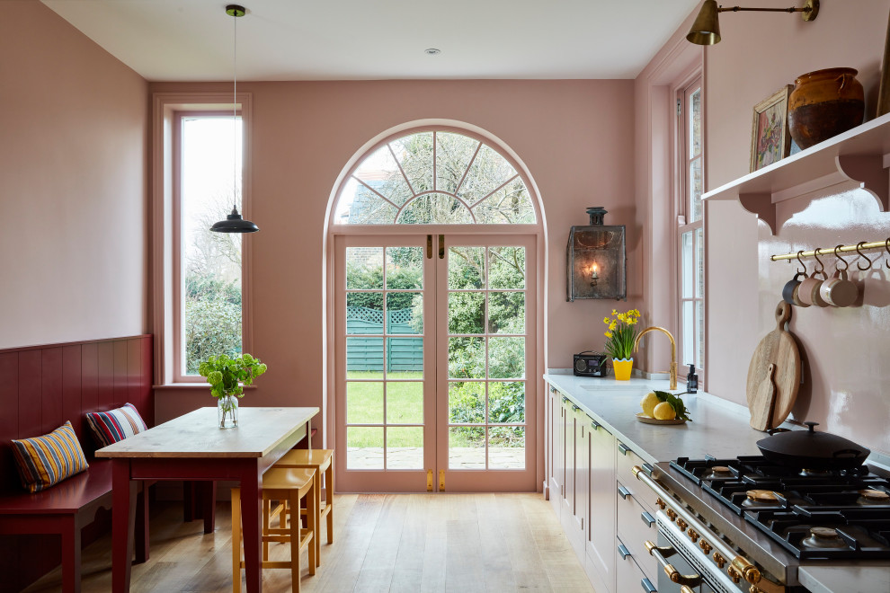 Design ideas for a mid-sized transitional single-wall eat-in kitchen in London with an undermount sink, shaker cabinets, pink splashback, glass sheet splashback, no island, beige floor and grey benchtop.