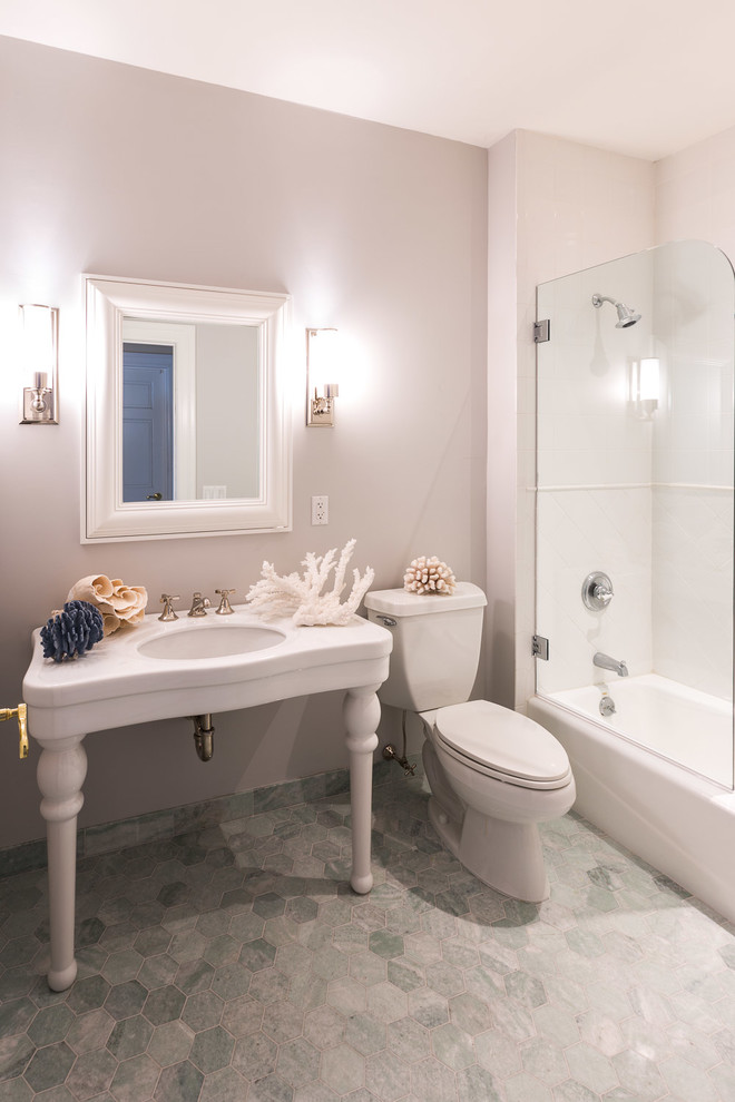 Photo of a mid-sized transitional bathroom in New York with open cabinets, white cabinets, an alcove tub, a shower/bathtub combo, a two-piece toilet, green tile, stone tile, grey walls, marble floors and a console sink.
