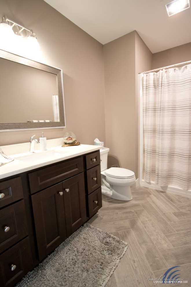 This is an example of a large transitional master bathroom in Other with shaker cabinets, brown cabinets, a drop-in tub, a shower/bathtub combo, a two-piece toilet, beige walls, porcelain floors, an undermount sink, engineered quartz benchtops, grey floor, a shower curtain, white benchtops, a single vanity and a built-in vanity.