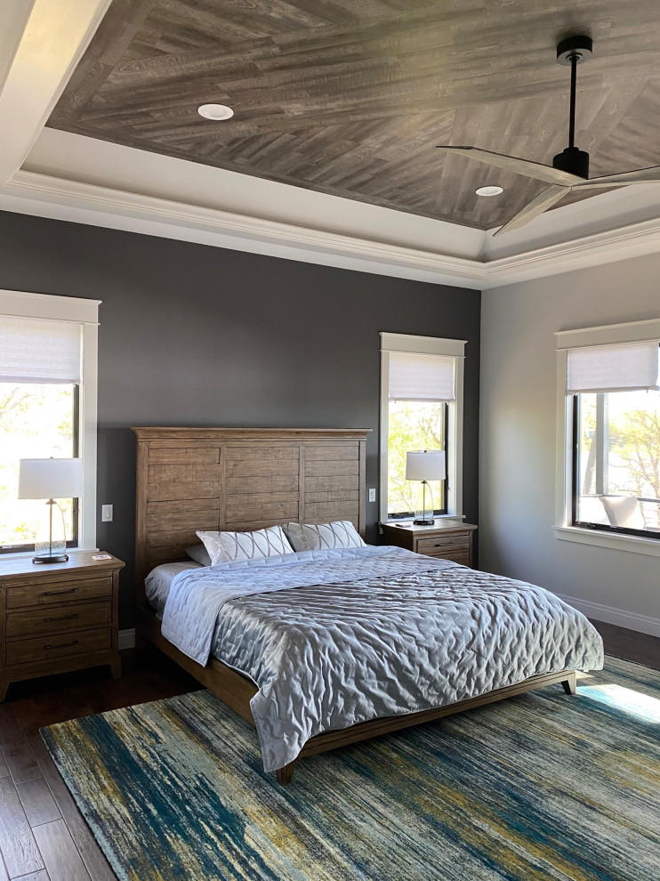 Imagen de dormitorio principal y gris rústico con paredes grises, suelo de madera en tonos medios y suelo marrón