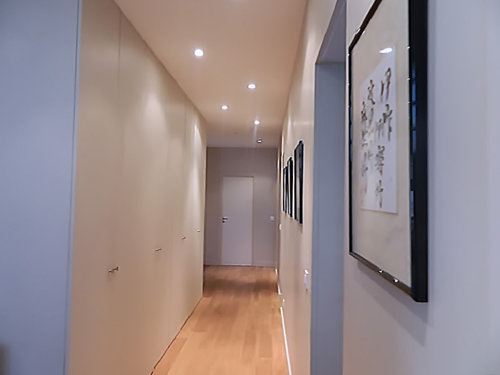Inspiration pour un grand couloir design avec un mur beige et parquet clair.