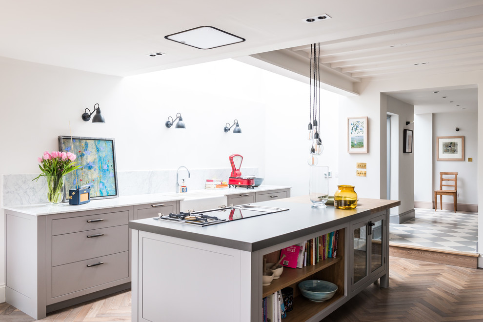 Inspiration for a large contemporary u-shaped eat-in kitchen in London with an undermount sink, flat-panel cabinets, grey cabinets, solid surface benchtops, white splashback, marble splashback, stainless steel appliances, light hardwood floors and with island.