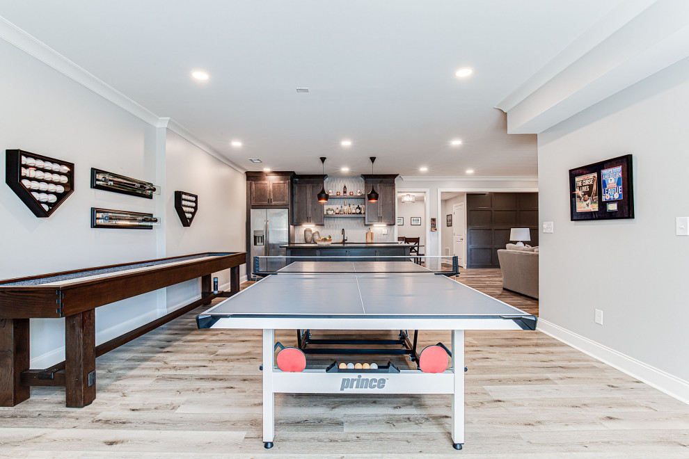 Inspiration for a large country walk-out basement in Atlanta with a game room, grey walls, vinyl flooring, a standard fireplace, a timber clad chimney breast, multi-coloured floors and wainscoting.