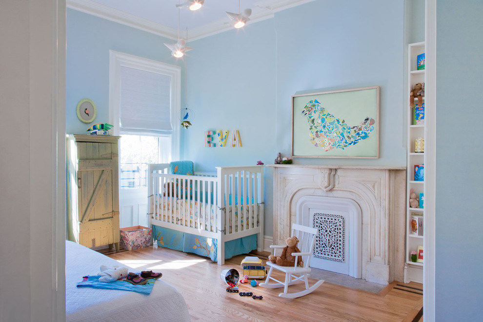 Photo of a transitional gender-neutral nursery in Chicago with blue walls and light hardwood floors.