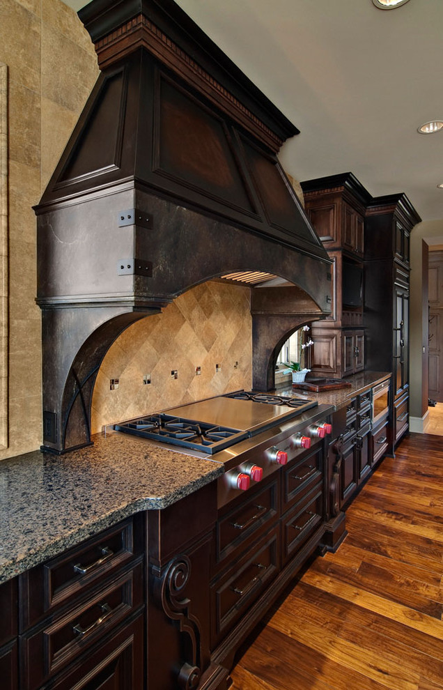 Inspiration for a traditional kitchen in Minneapolis with raised-panel cabinets, dark wood cabinets, quartz benchtops, brown splashback, stone tile splashback, stainless steel appliances and medium hardwood floors.