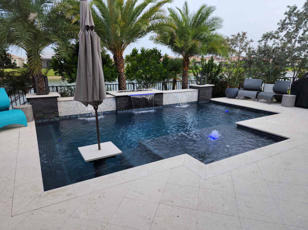 Aménagement d'une piscine arrière contemporaine avec des pavés en pierre naturelle.