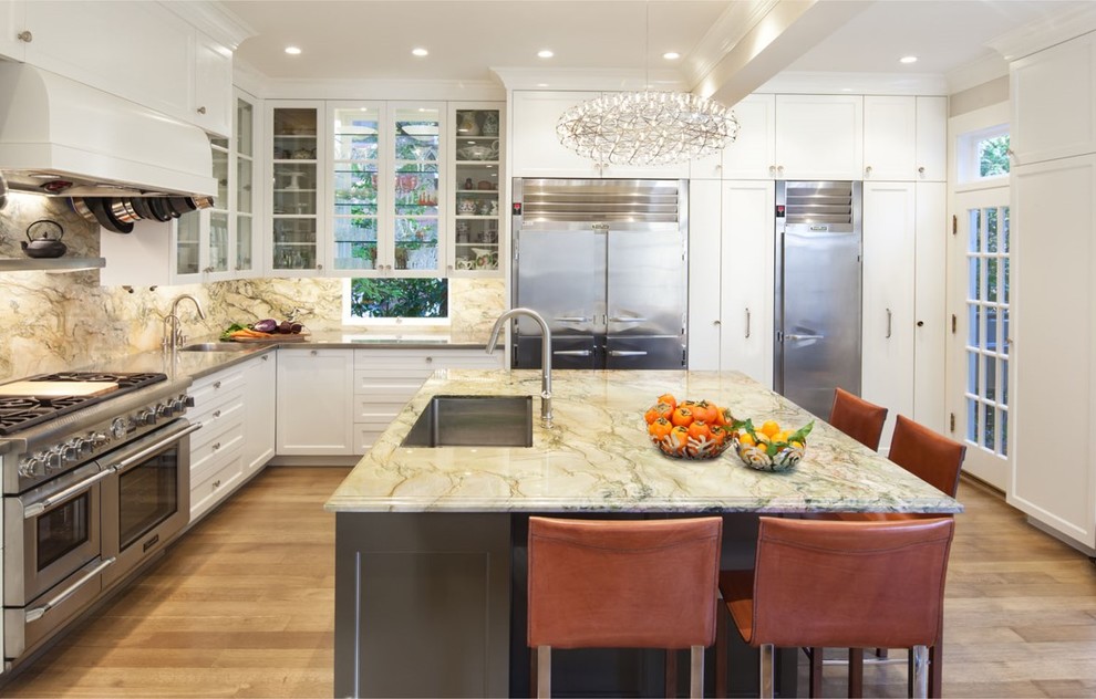 Large contemporary l-shaped eat-in kitchen in San Francisco with an integrated sink, glass-front cabinets, white cabinets, quartzite benchtops, stainless steel appliances, medium hardwood floors, with island, multi-coloured splashback, stone slab splashback and beige floor.