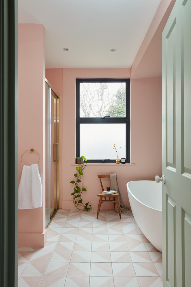 Foto på ett mellanstort funkis flerfärgad badrum för barn, med ett fristående badkar, en kantlös dusch, en vägghängd toalettstol, rosa kakel, keramikplattor, rosa väggar, cementgolv, ett väggmonterat handfat, bänkskiva i terrazo, rosa golv och dusch med skjutdörr