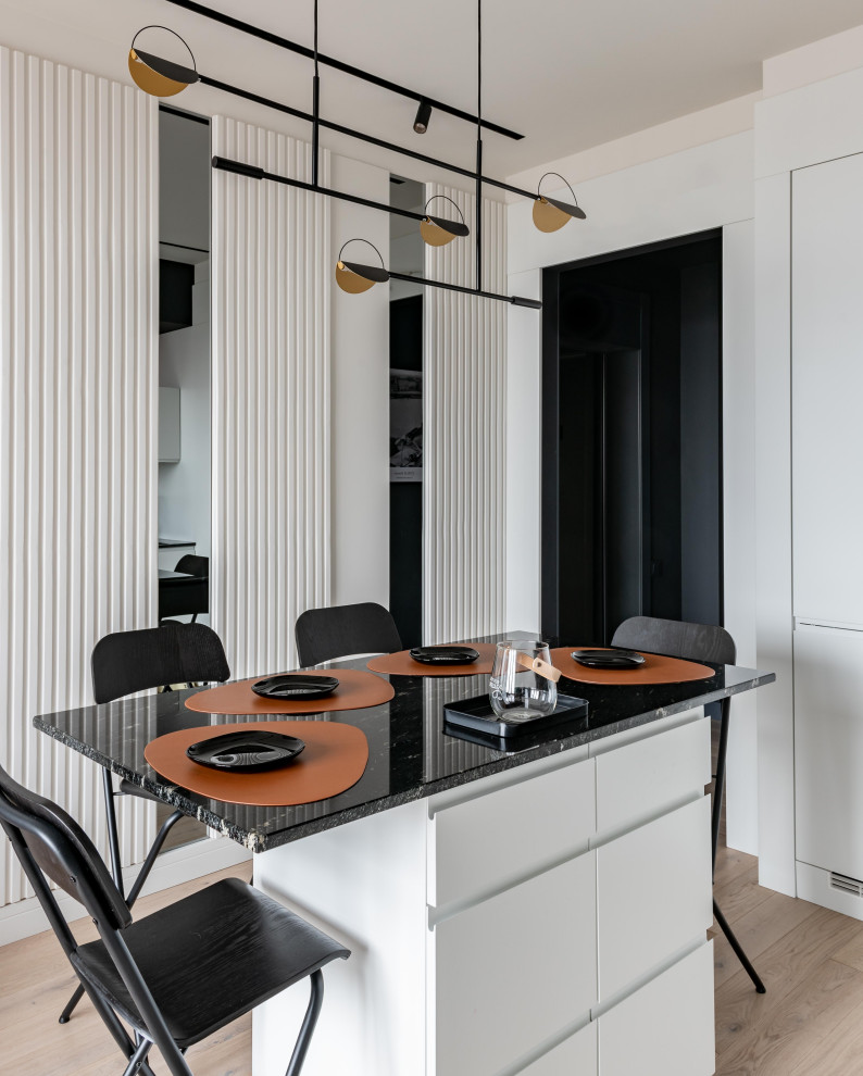 Design ideas for a small scandinavian single-wall eat-in kitchen in Moscow with an undermount sink, flat-panel cabinets, white cabinets, granite benchtops, black splashback, granite splashback, black appliances, light hardwood floors, with island, grey floor and black benchtop.