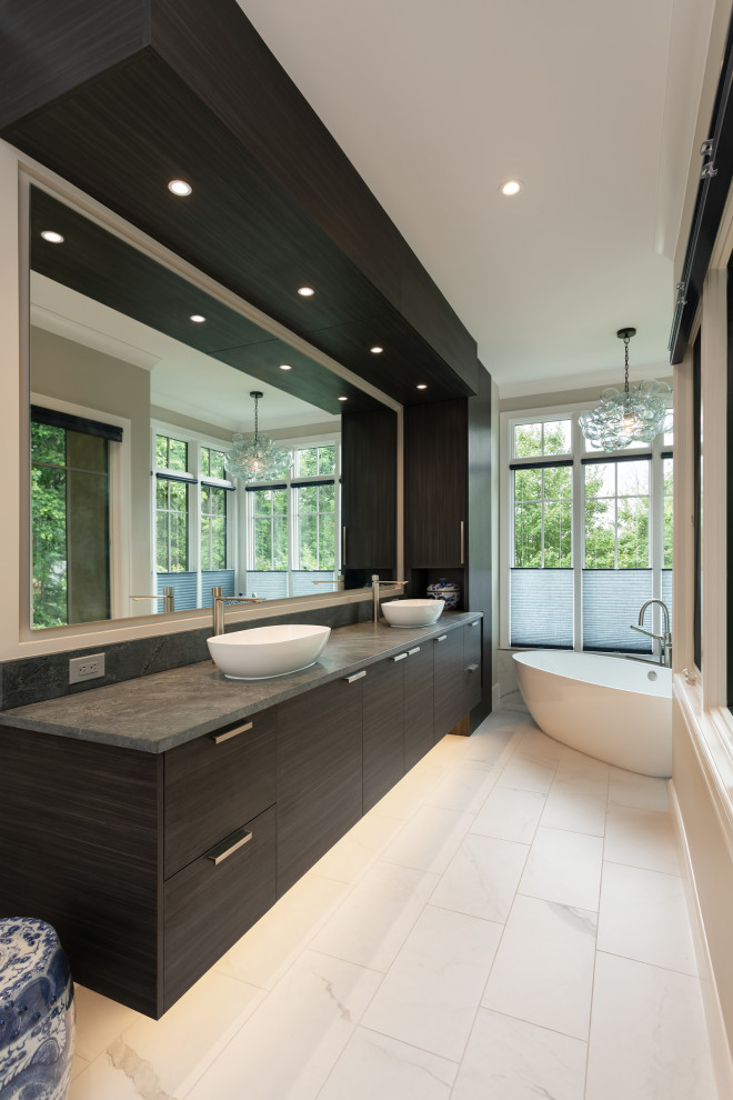 Design ideas for a large contemporary master bathroom in Other with flat-panel cabinets, dark wood cabinets, a freestanding tub, an open shower, a bidet, white tile, porcelain tile, porcelain floors, a vessel sink, soapstone benchtops, white floor, an open shower, grey benchtops, an enclosed toilet, a double vanity and a built-in vanity.