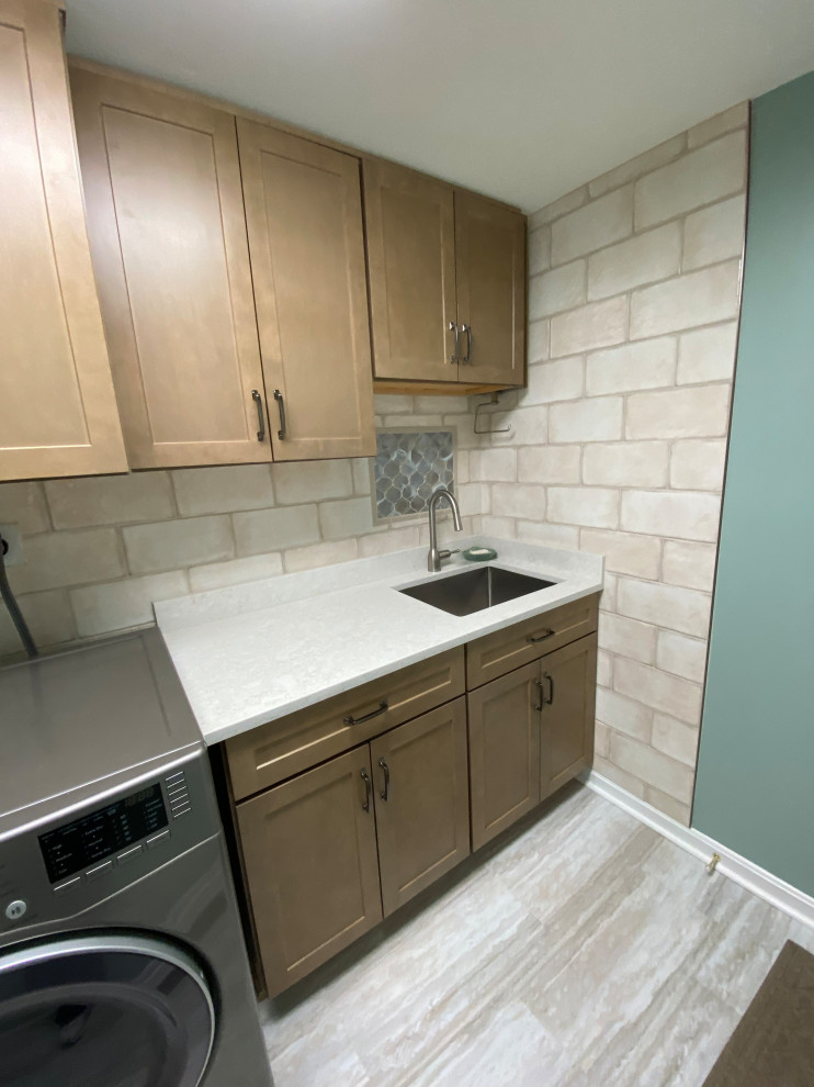 This is an example of a mid-sized galley dedicated laundry room in Baltimore with an undermount sink, recessed-panel cabinets, medium wood cabinets, quartz benchtops, white splashback, ceramic splashback, white walls, vinyl floors, a side-by-side washer and dryer, green floor and white benchtop.