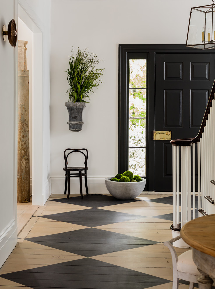 This is an example of a transitional front door with white walls, painted wood floors, a single front door and a black front door.