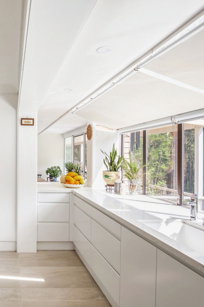 Inspiration för stora moderna vitt kök, med en undermonterad diskho, släta luckor, vita skåp, bänkskiva i kvarts, fönster som stänkskydd, rostfria vitvaror och ljust trägolv